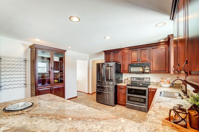 kitchen featuring appliances with stainless steel finishes, sink, and light stone countertops