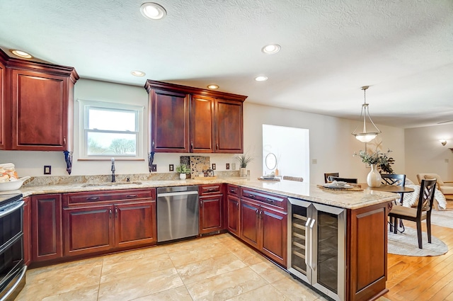 kitchen featuring sink, dishwasher, wine cooler, kitchen peninsula, and hanging light fixtures