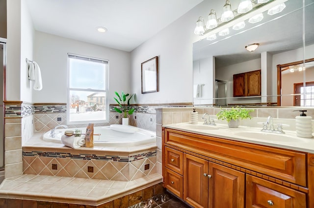 bathroom featuring tiled tub, vanity, and a healthy amount of sunlight