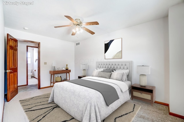 bedroom featuring light carpet, ensuite bathroom, and ceiling fan