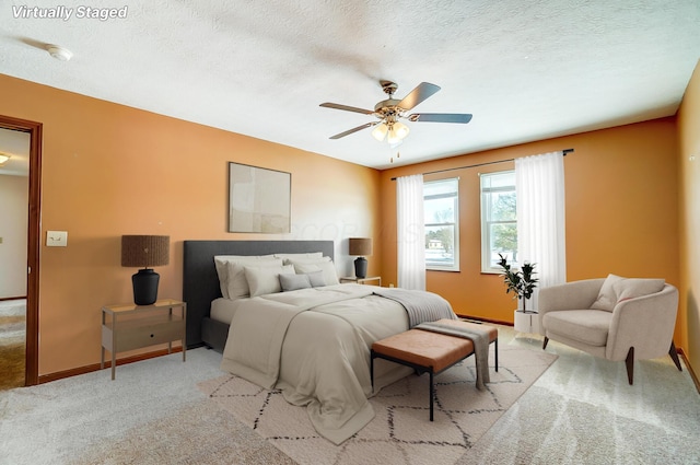 bedroom with ceiling fan, a textured ceiling, and light colored carpet