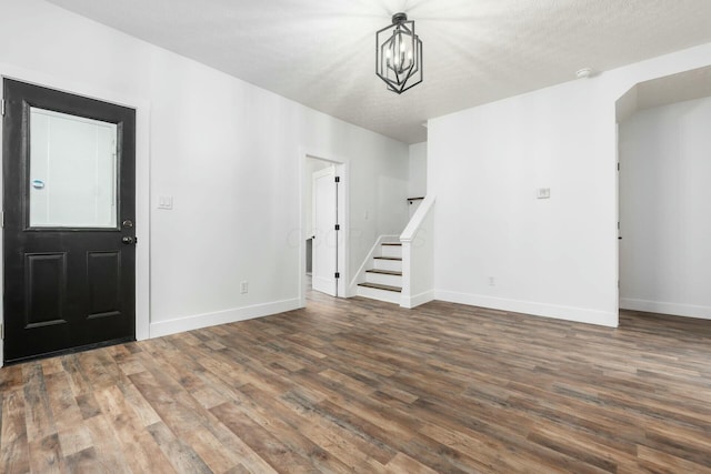 foyer entrance featuring dark wood-type flooring, a chandelier, and a textured ceiling