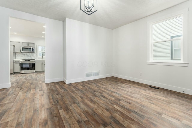 unfurnished dining area featuring dark hardwood / wood-style flooring and an inviting chandelier