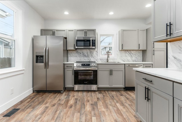 kitchen featuring stainless steel appliances, tasteful backsplash, gray cabinetry, and sink