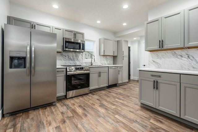 kitchen with sink, dark wood-type flooring, appliances with stainless steel finishes, and gray cabinets