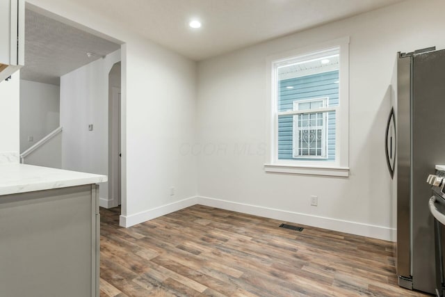 kitchen with light stone counters, stainless steel fridge, and dark hardwood / wood-style flooring