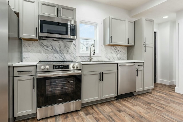 kitchen featuring appliances with stainless steel finishes, gray cabinets, sink, and dark wood-type flooring