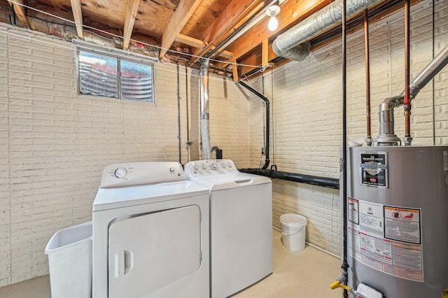 washroom featuring brick wall, water heater, and separate washer and dryer