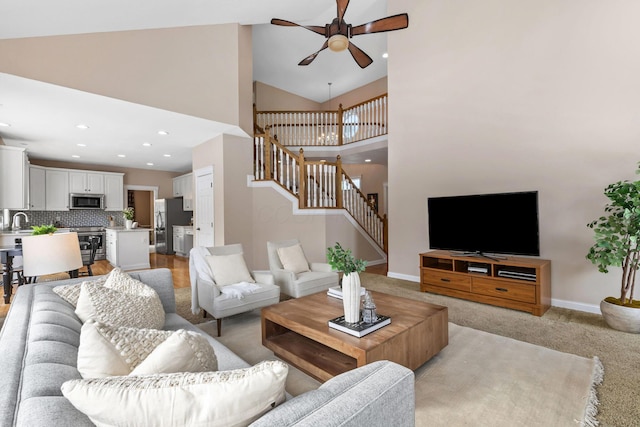 living area with high vaulted ceiling, recessed lighting, a ceiling fan, baseboards, and stairway