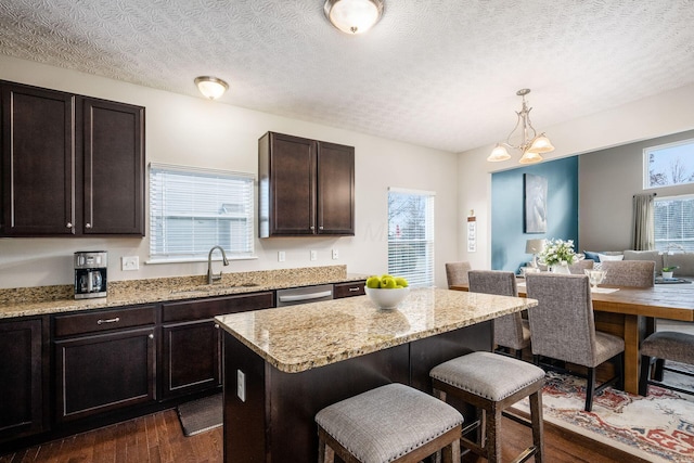 kitchen with dark brown cabinetry, sink, a center island, hanging light fixtures, and a kitchen breakfast bar