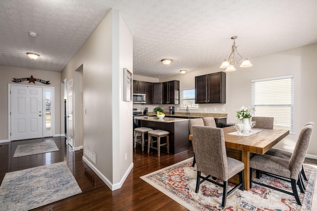 dining space with dark hardwood / wood-style floors, sink, a textured ceiling, and a notable chandelier