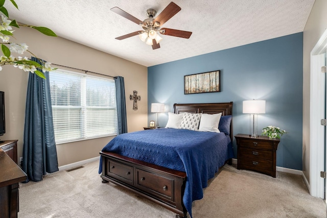 bedroom featuring ceiling fan, light colored carpet, and a textured ceiling