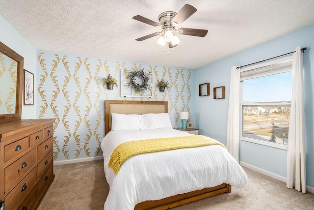 carpeted bedroom featuring ceiling fan and a textured ceiling