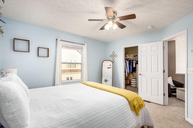 carpeted bedroom featuring ceiling fan, a spacious closet, a closet, and a textured ceiling