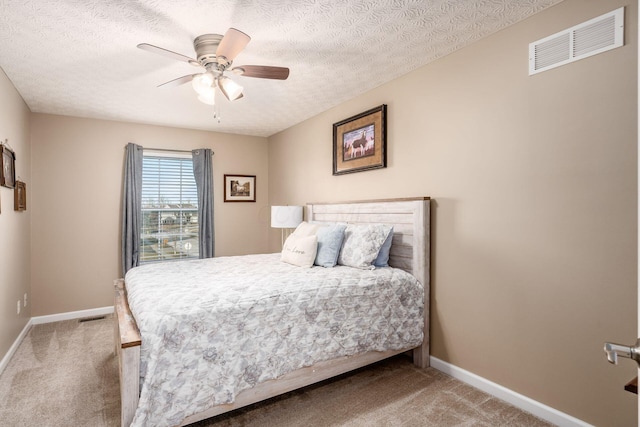 bedroom with ceiling fan, carpet, and a textured ceiling