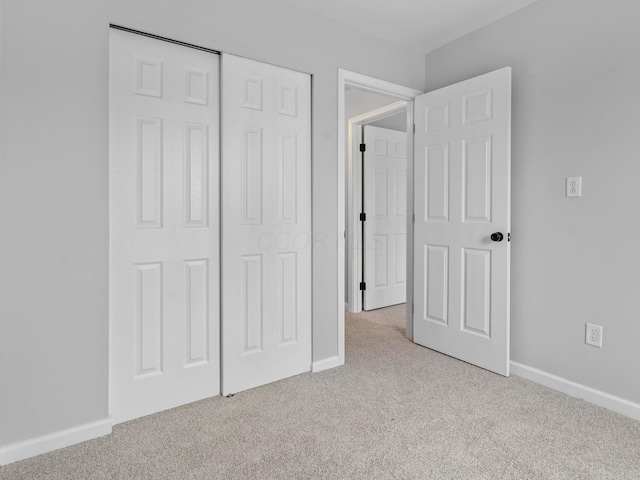 unfurnished bedroom with light colored carpet and a closet