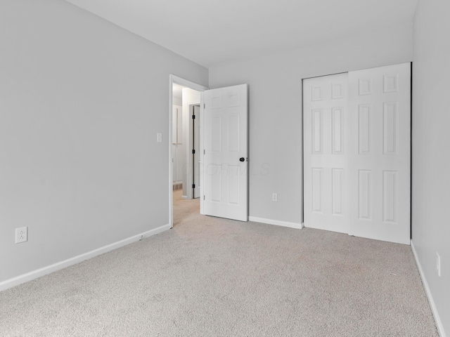 unfurnished bedroom featuring light carpet and a closet