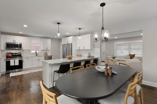 dining space featuring a healthy amount of sunlight, sink, and dark hardwood / wood-style flooring