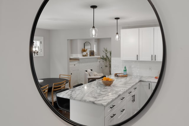 kitchen with white cabinetry, decorative light fixtures, light stone countertops, and tasteful backsplash