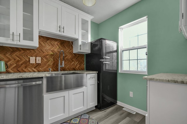 kitchen with black refrigerator, backsplash, dishwasher, and white cabinets