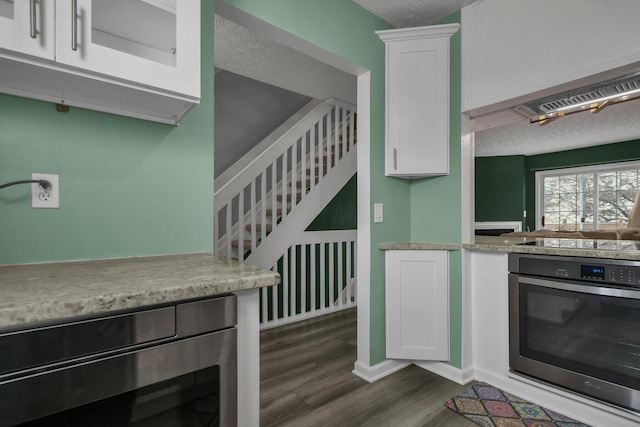 kitchen featuring white cabinets, stainless steel oven, dark wood-type flooring, a textured ceiling, and black electric cooktop