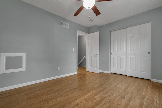 unfurnished bedroom with ceiling fan, light hardwood / wood-style floors, a closet, and a textured ceiling