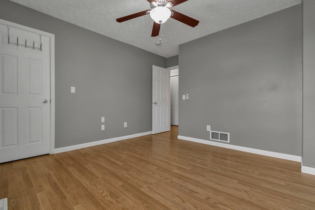 empty room with ceiling fan, a textured ceiling, and light hardwood / wood-style flooring