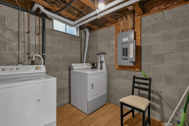 laundry room featuring electric panel, washer and dryer, and light wood-type flooring