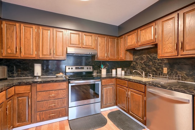 kitchen featuring stainless steel appliances, sink, light hardwood / wood-style flooring, and decorative backsplash