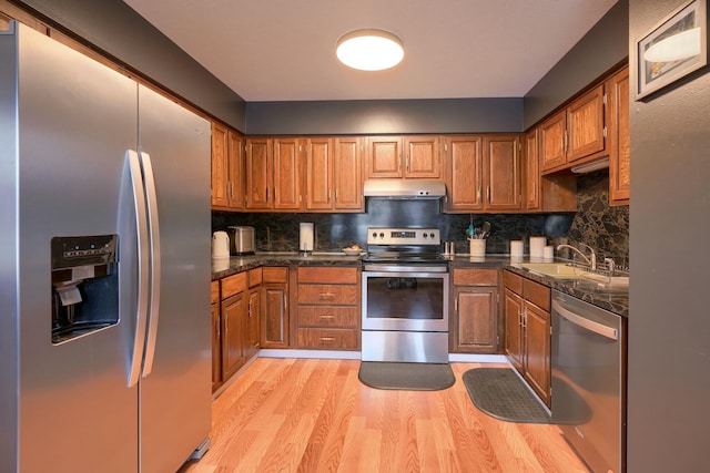 kitchen with backsplash, appliances with stainless steel finishes, sink, and light wood-type flooring