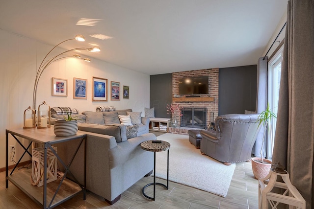 living room with a brick fireplace and light wood-type flooring