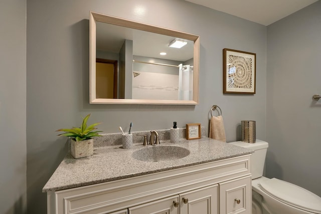 bathroom with walk in shower, vanity, and toilet