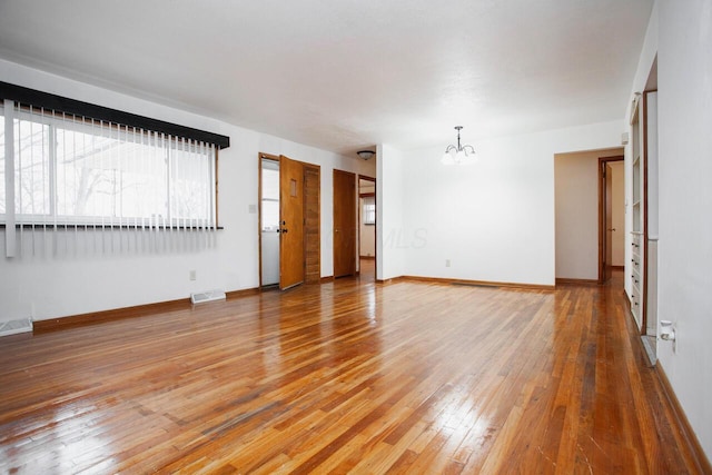 unfurnished room featuring a chandelier and hardwood / wood-style floors