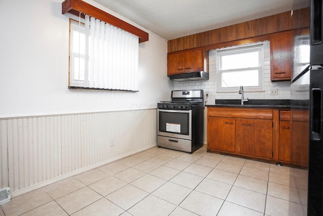 kitchen with light tile patterned flooring, stainless steel range with gas cooktop, sink, and backsplash