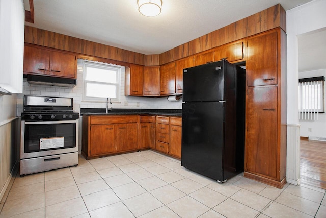 kitchen with black refrigerator, gas range, decorative backsplash, and a wealth of natural light