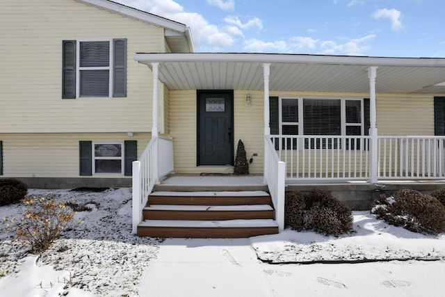 snow covered property entrance featuring covered porch