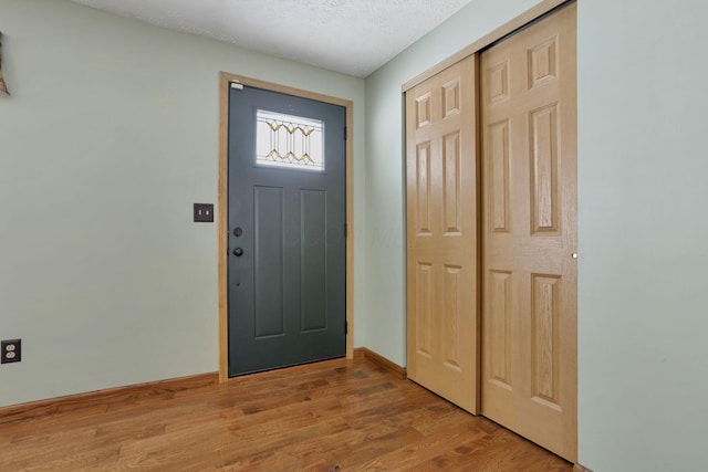 entrance foyer featuring a textured ceiling, light wood-style flooring, and baseboards