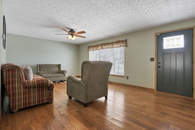 living room featuring a textured ceiling, wood finished floors, and a ceiling fan