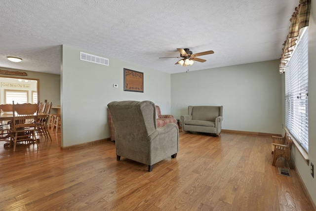 living room with light wood-style flooring, visible vents, and a textured ceiling