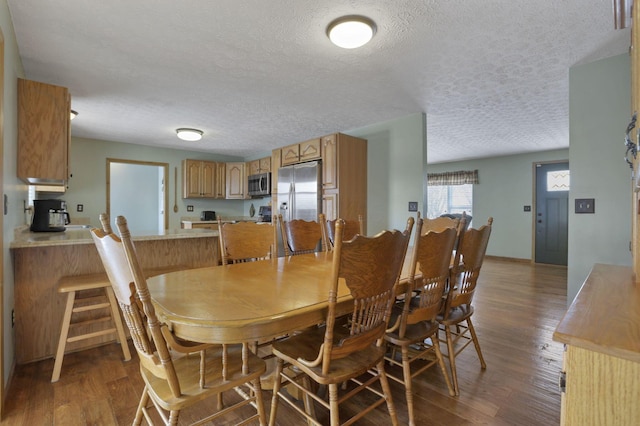 dining area featuring a textured ceiling and dark wood-style flooring