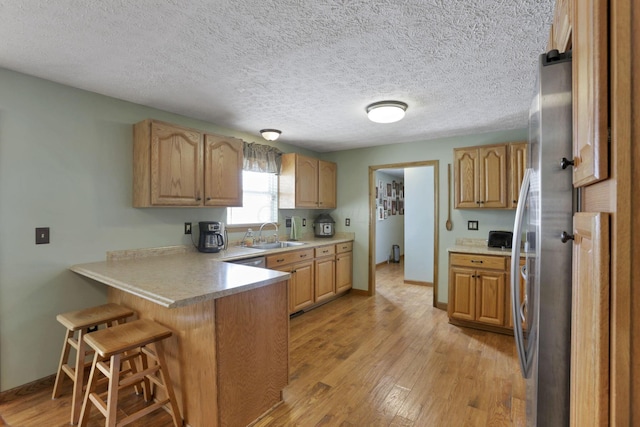 kitchen featuring light wood-style floors, light countertops, a peninsula, and a kitchen bar