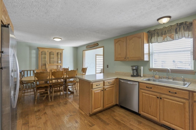 kitchen with a peninsula, stainless steel appliances, a sink, and light countertops