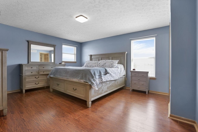 bedroom featuring dark wood-type flooring, a textured ceiling, and baseboards