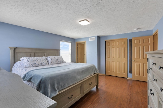 bedroom featuring visible vents, dark wood finished floors, and a textured ceiling