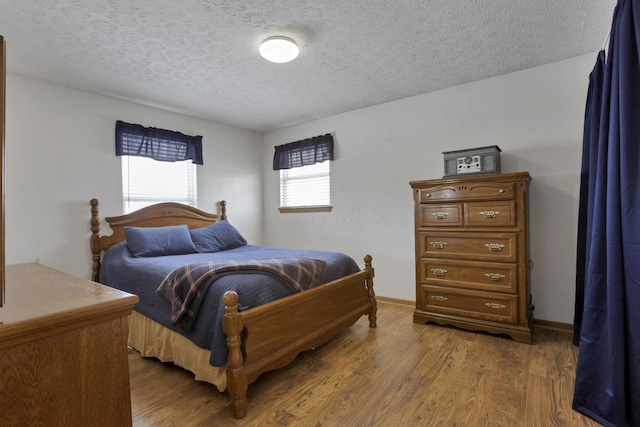 bedroom featuring dark wood finished floors, a textured ceiling, and baseboards