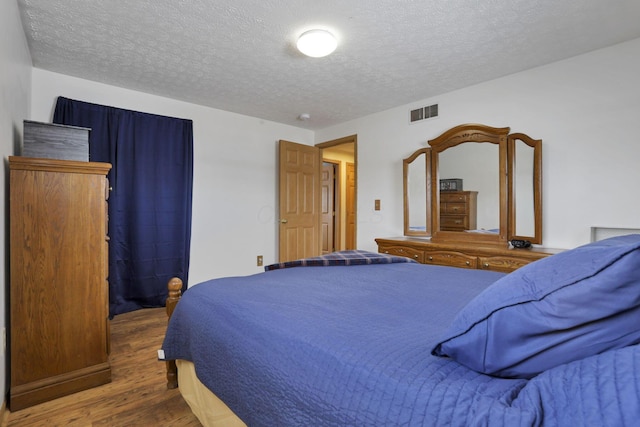 bedroom featuring a textured ceiling, visible vents, and dark wood-style flooring