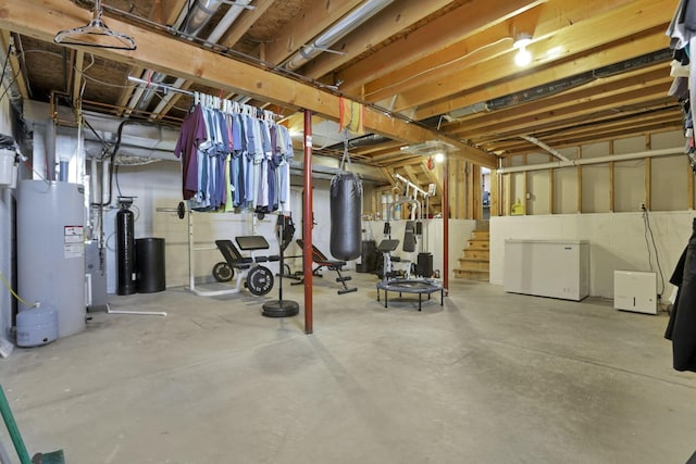 unfinished basement featuring stairs and water heater