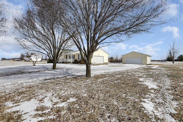 snowy yard featuring a detached garage