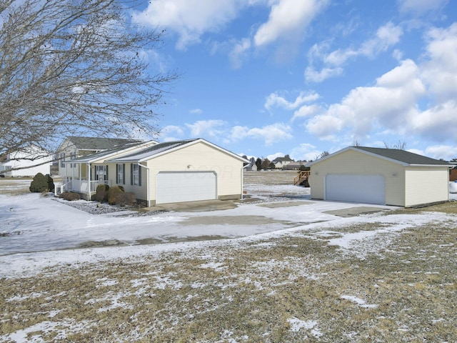 snow covered property with a detached garage