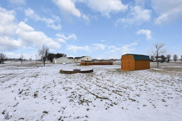 snowy yard featuring an outdoor structure and a storage unit